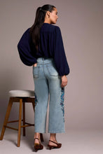 Load image into Gallery viewer, Woman wearing a navy blue top and light blue jeans with floral embroidery and brown heels standing against a plain background.