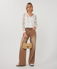Load image into Gallery viewer, Woman wearing a white lace top and brown wide-leg pants, holding a woven handbag on a white background.