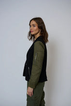 Load image into Gallery viewer, Woman wearing a black and green blazer over a white tank and green pants against a white background.