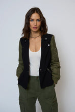 Load image into Gallery viewer, Woman wearing a black and green blazer over a white tank and green pants against a white background.