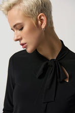 Load image into Gallery viewer, The Joseph Ribkoff long sleeve top features a slim silhouette, bow detail at the neckline, and an ultra-soft, stretchy fabric, allowing you to flaunt a feminine appearance. Ideal for wearing alone or for blending with a blazer, its design ensures a comfortable fit while elevating your look. Color- Black. Bow design detail at the neck. Keyhole neckline. Fabric -96% Polyester, 4% Spandex.