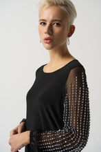 Load image into Gallery viewer, This luxurious tunic is crafted from a silky knit fabric, with mesh puff sleeves for a touch of drama. The asymmetrical design is flattering and feminine, while the beading detail adds a touch of glamour. Color - Black. Silky knit with mesh. Beading on sleeves. Boat neckline. Puff sleeves. Asymmetrical hem. Unlined.