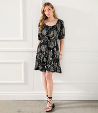 Load image into Gallery viewer, A charming scarf print puts a bohemian focus on this summer-ready dress. This statement-making dress features peasant sleeves, a tiered hem and flattering cinched waist and matching belt. Colors- Black and white. Short puff sleeve. Side pockets. Self-tie belt. Tiered hem. Cinched waist.