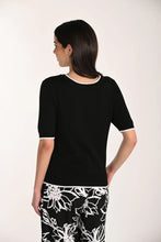 Load image into Gallery viewer, Woman wearing a black top and floral pants on a white background.