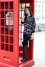 Load image into Gallery viewer, This sleek button-down tunic top dazzles with its bold white lettering on a black backdrop for a classic and eye-catching look. The back is sure to turn heads with its striking face and rhinestone glasses silhouette, creating a stylish look that exudes confidence and sophistication. Color- Black, white, red, orange, blue/gray, tan. Button-down. Tunic length.