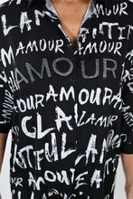 Load image into Gallery viewer, This sleek button-down tunic top dazzles with its bold white lettering on a black backdrop for a classic and eye-catching look. The back is sure to turn heads with its striking face and rhinestone glasses silhouette, creating a stylish look that exudes confidence and sophistication. Color- Black, white, red, orange, blue/gray, tan. Button-down. Tunic length.