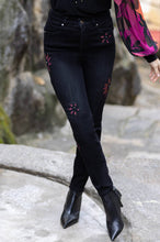 Load image into Gallery viewer, These black straight leg jeans crafted from exceptional denim feature eye-catching hand-painted motifs of bright magenta flowers, which are further accented with sequins and rhinestones for a dazzling finish. Make a bold style statement and stand out from the crowd in these extraordinary jeans. Color- Black and magenta. Slim leg design. Painted floral designs with sequin and rhinestones. Floral designs on front side only. Five functional pockets. Zipper and button closure.