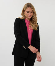 Load image into Gallery viewer, Woman wearing a black blazer with gold buttons over a pink shirt and black pants against a white background.