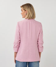 Load image into Gallery viewer, Woman wearing a pink blazer and blue jeans on a plain background.