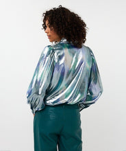 Load image into Gallery viewer, Model wearing a teal, blue and silver blouse with teal pants against a white background.