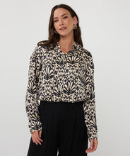 Load image into Gallery viewer, Woman wearing an abstract print top in black and beige and black pants against a white background.