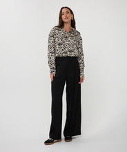 Load image into Gallery viewer, Woman wearing an abstract print top in black and beige, black pants and black sneakers against a white background.