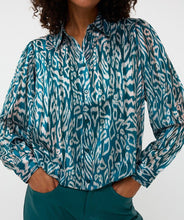 Load image into Gallery viewer, Woman wearing a teal and white with shimmer patterned blouse and teal pants against a white background.