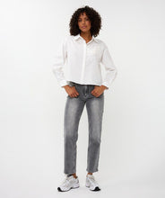 Load image into Gallery viewer, Woman wearing a white blouse with floral embroidery, jeans and white sneakers against a white background.