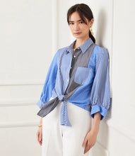 Load image into Gallery viewer, Woman wearing a blue and gray striped shirt against a white background.