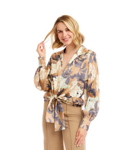Load image into Gallery viewer, Woman wearing a tie waist patterned long sleeve blouse in floral grey, cream and tan and tan pants against a neutral background.