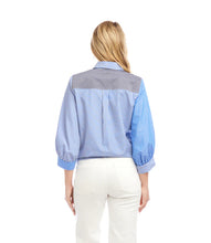 Load image into Gallery viewer, Woman wearing a blue and gray striped shirt and white jeans against a white background.
