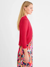 Load image into Gallery viewer, Woman wearing a red bolero cardigan over a colorful floral dress against a white background.