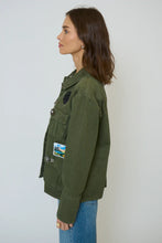Load image into Gallery viewer, Woman wearing green shacket with patches and blue jeans against a neutral background.