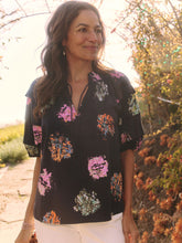 Load image into Gallery viewer, Sometimes it's all in the name! This dramatic combo of dark background and powerful pops of color on this stunning top is an outfit scene stealer, a real conversation piece. It's not just the firework display design though: we love the layered details on the short sleeves, the easy elastic cuffs, the frilled split neck, and the tie front. Dress it up with professional workpants or keep things casual with denim.