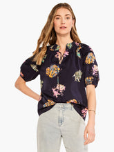 Load image into Gallery viewer, Sometimes it's all in the name! This dramatic combo of dark background and powerful pops of color on this stunning top is an outfit scene stealer, a real conversation piece. It's not just the firework display design though: we love the layered details on the short sleeves, the easy elastic cuffs, the frilled split neck, and the tie front. Dress it up with professional workpants or keep things casual with denim.