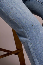 Load image into Gallery viewer, Close-up of model sitting on a stool wearing blue jeans with tiny rhinestones.