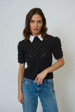 Load image into Gallery viewer, Woman wearing a black knit top with a white collar and blue jeans against a plain background.