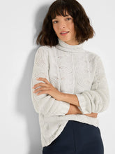 Load image into Gallery viewer, Woman wearing a light grey cable sweater with sequins and black pants against a plain background.