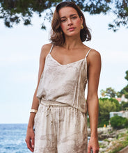 Load image into Gallery viewer, Woman wearing a beige and white safari patterned camisole and matching pant standing by the ocean with trees and buildings in the background.