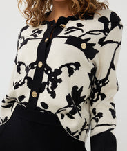 Load image into Gallery viewer, Add a touch of sophistication to your wardrobe with our Short Two-Tone Jacquard Cardigan. This stylish cardigan features a unique two-tone jacquard knit in a floral pattern and includes shiny upscale buttons, creating a chic and elegant look. The round neckline and long sleeves provide a classic silhouette, while the ribbing at the neckline, cuffs, and hem adds a polished finish. Perfect for layering over a simple dress or pairing with jeans for a trendy, effortless style.