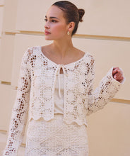 Load image into Gallery viewer, Woman wearing a natural color crochet cardigan and matching skirt against a neutral color wall.