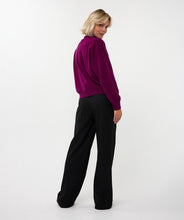 Load image into Gallery viewer, Woman wearing a purple sweater cardigan and black pants against a white background.