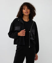 Load image into Gallery viewer, Woman wearing a black jacket and pants against a white background.