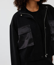 Load image into Gallery viewer, Black jacket with a zipper and satin pockets against a white background.