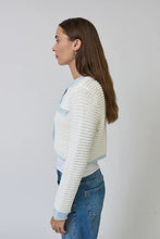 Load image into Gallery viewer, Woman wearing a white textured sweater with light blue contrast stitching and blue jeans on a plain background.