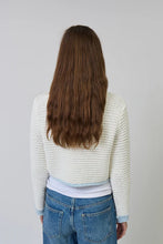 Load image into Gallery viewer, Woman wearing a white textured sweater with light blue contrast stitching and blue jeans on a plain background.