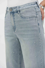Load image into Gallery viewer, Upgrade your denim collection with the Joseph Ribkoff Coralie Classic Wide Leg Stretch Jeans, a stunning fusion of sophistication, comfort, and sustainability. Designed for the modern woman who craves effortless style, these eco-friendly Repreve® stretch denim jeans provide a flattering wide-leg silhouette adorned with dazzling crystal embellishments for that extra touch of glamour.