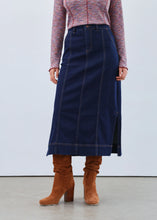 Load image into Gallery viewer, Woman wearing a patterned top, long denim skirt and brown boots against a white background.