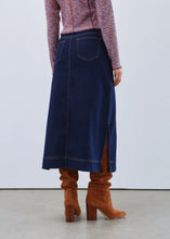 Load image into Gallery viewer, Woman wearing a patterned top, long denim skirt and brown boots against a white background.