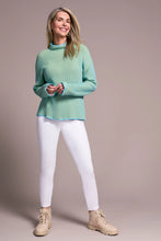 Load image into Gallery viewer, Woman wearing a teal blue sweater, white leggings and tan boots against a pale pink background.