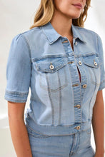 Load image into Gallery viewer, Woman wearing a short sleeve, light blue denim jacket and jeans against a light background.