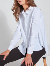 Load image into Gallery viewer, A woman wearing a white long-sleeve button-up shirt and black pants, seated on a white chair against a light gray background.