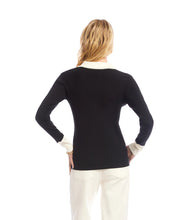 Load image into Gallery viewer, Woman wearing a black sweater with white collar and cuffs and jeans against a white background.