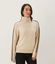 Load image into Gallery viewer, Woman wearing a color block turtleneck sweater with black contrast stitching down the arms and black pants standing against a white wall.