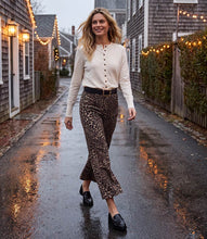 Load image into Gallery viewer, A woman walking down a wet, street-lit residential alley wearing a cream long-sleeve button-front top, cheetah-print flared pants, a black belt, and black loafers.