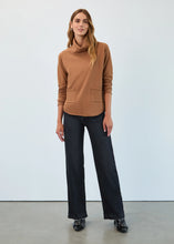 Load image into Gallery viewer, Woman wearing a bronze caramel cowl neck sweater, small hoop earrings, dark wash pants and black loafers against a white background.