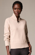 Load image into Gallery viewer, Woman wearing a beige sweater with a metallic closure detail and brown pants against a white background.