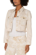 Load image into Gallery viewer, Add this fabulous, cropped denim layering piece to your entire look to add an edge to your outfit. Cropped at the waist, our Cynthia is the perfect length for versatility. The frayed hem and tie dye wash makes this unique style a fantastic choice for any outfit. For an effortless look, layer over an easy knit top with a looser fitting bottom for the perfect silhouette. Color - Bisquit Tan Tie Dye; washed light tan. Tie dye Silver buttons and hardware. D-ring on back. Crop style.