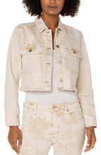 Load image into Gallery viewer, Add this fabulous, cropped denim layering piece to your entire look to add an edge to your outfit. Cropped at the waist, our Cynthia is the perfect length for versatility. The frayed hem and tie dye wash makes this unique style a fantastic choice for any outfit. For an effortless look, layer over an easy knit top with a looser fitting bottom for the perfect silhouette. Color - Bisquit Tan Tie Dye; washed light tan. Tie dye Silver buttons and hardware. D-ring on back. Crop style.