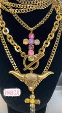 Load image into Gallery viewer, Stunning crystals atop an antique gold-plated brass base make this 32" Ombre Cross necklace a must-have for any wardrobe. Perfect for wearing long or doubled up for a shorter style, the Canadian-made piece will take your look to the next level. Make a statement and express your unique style with this eye-catching necklace. Color- Gold, pink, blue, purple, champagne Crystals. Antique gold-plated brass metal. Length- 32 inches. Can be doubled up for a shorter style.